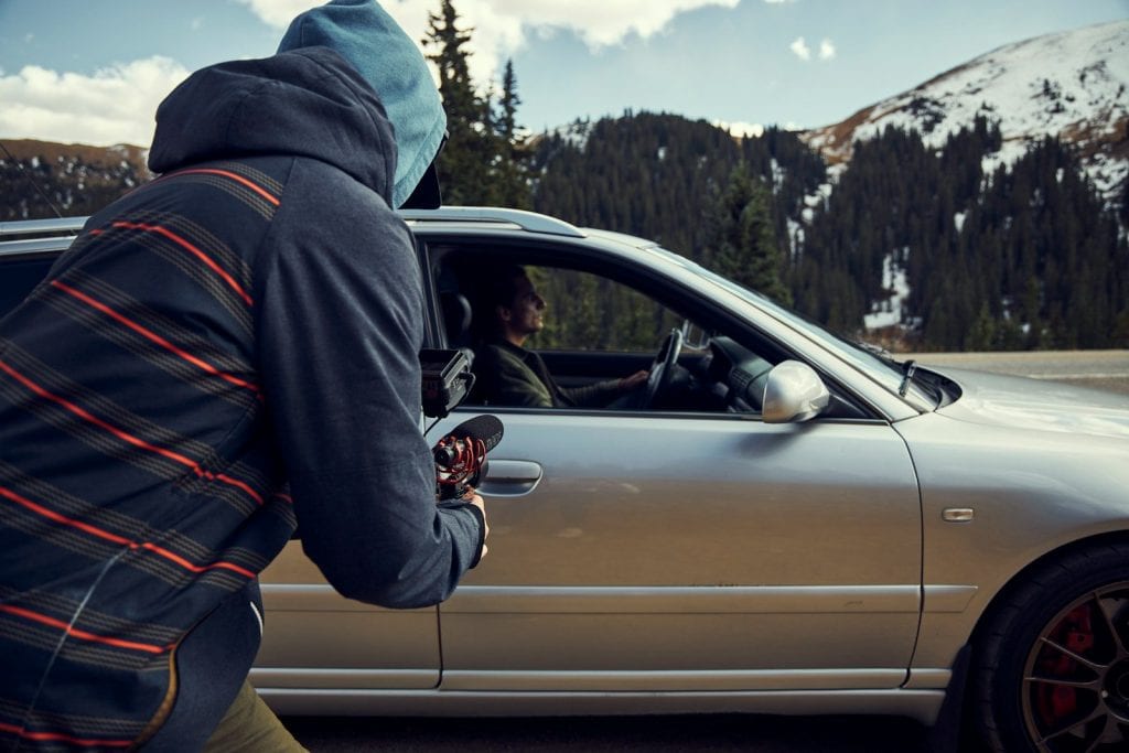 a man in a hoodie is looking out the window of a car