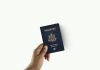 Citizenship Application Fee Increase Could Double Costs a hand holding a passport over a white background