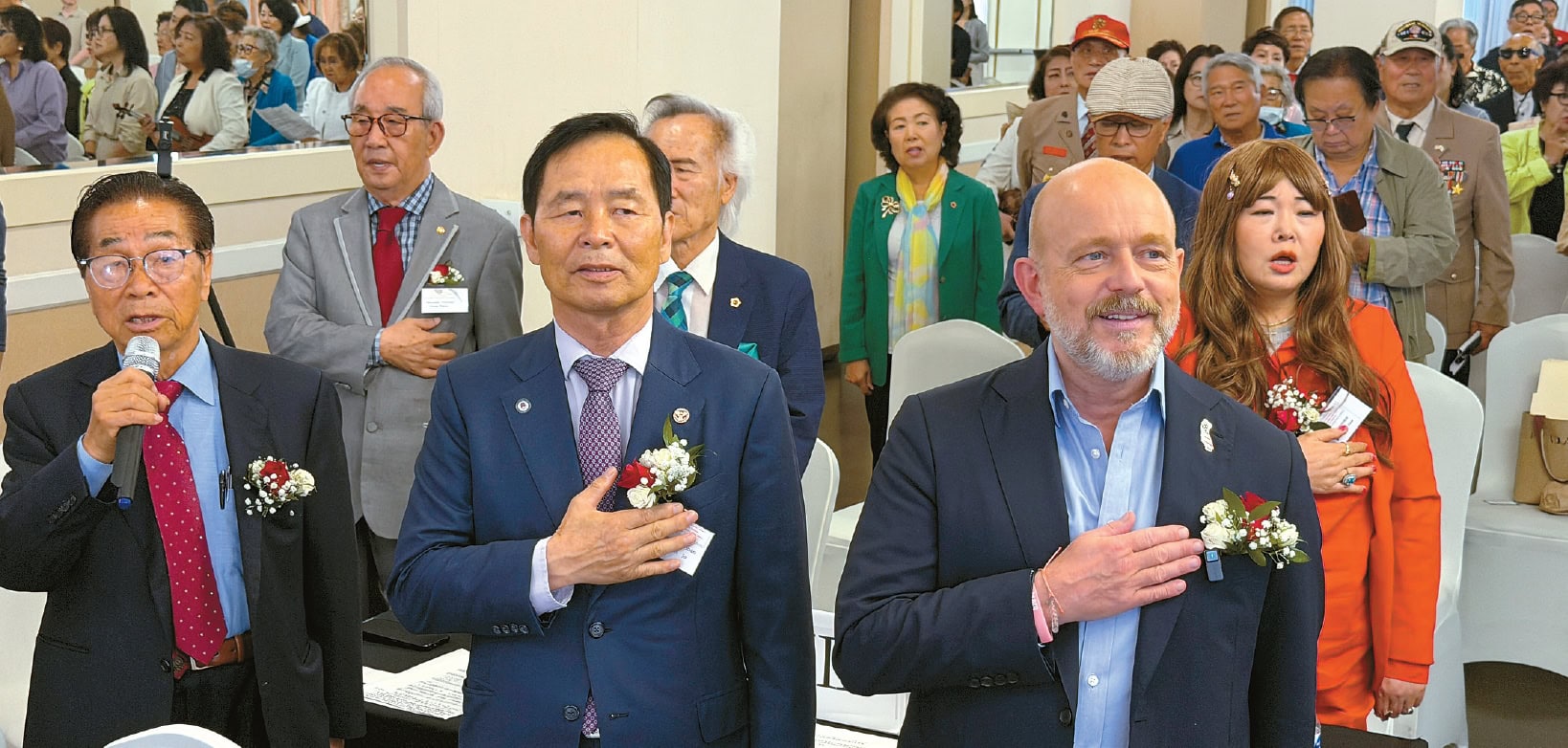Steve Hilton and attendees salute the American flag at a Koreatown town hall meeting.