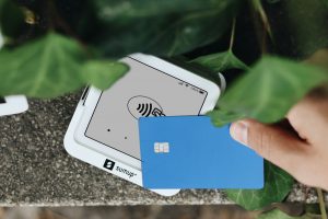 A hand holding a credit card next to a cell phone
