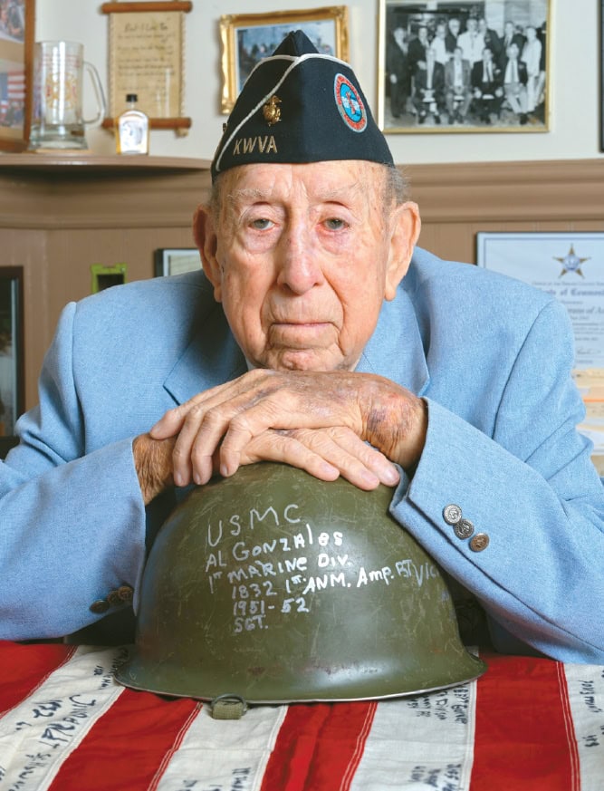 Korean War veteran Albert Gonzales rests his chin on a helmet marked with his military unit and Korean War service dates.