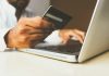 Inflation, High Interest Rates Drive Record Demand for Debt Consolidation person using laptop computer holding card